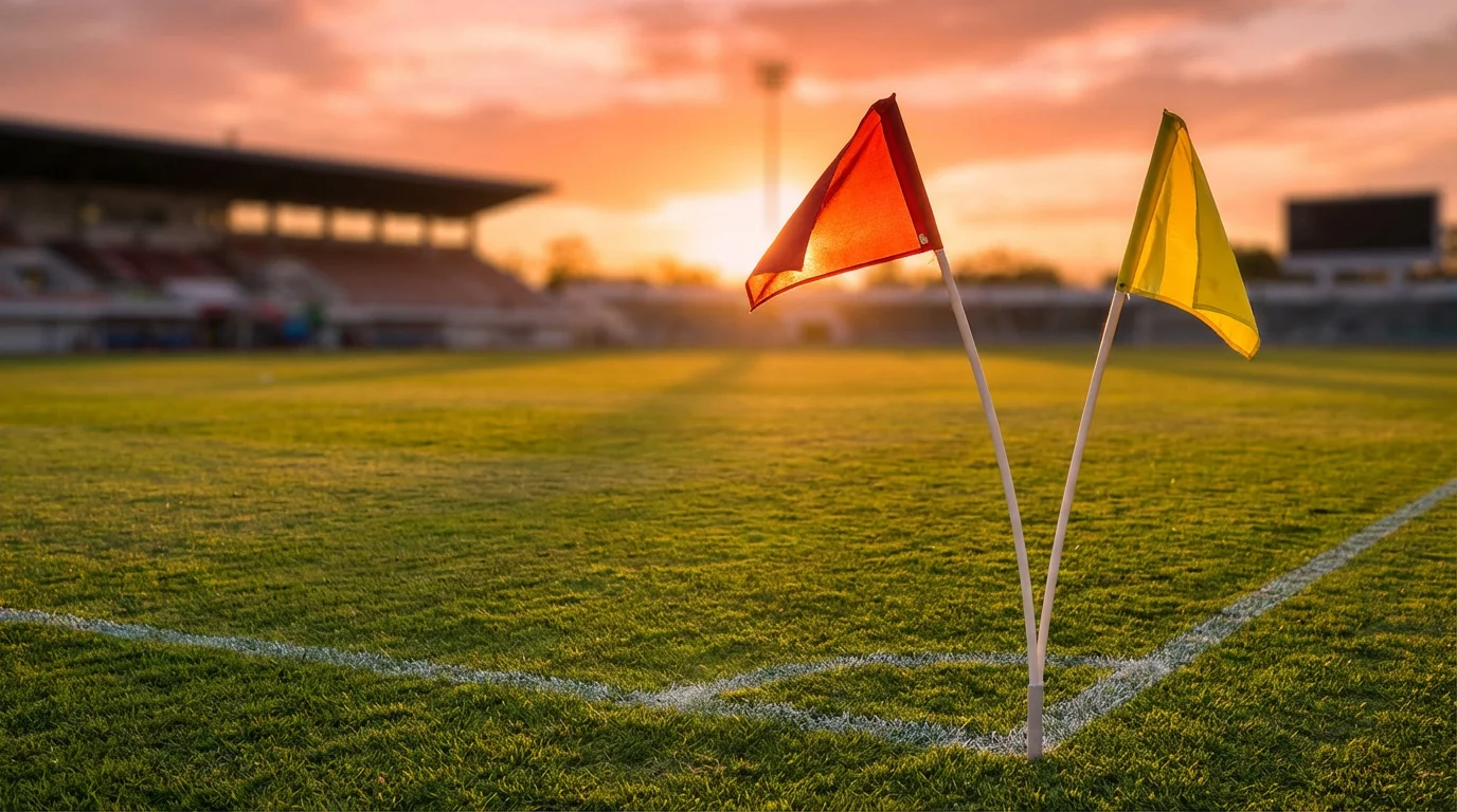 Bandierine d'angolo colorate su un campo da calcio illuminato al tramonto